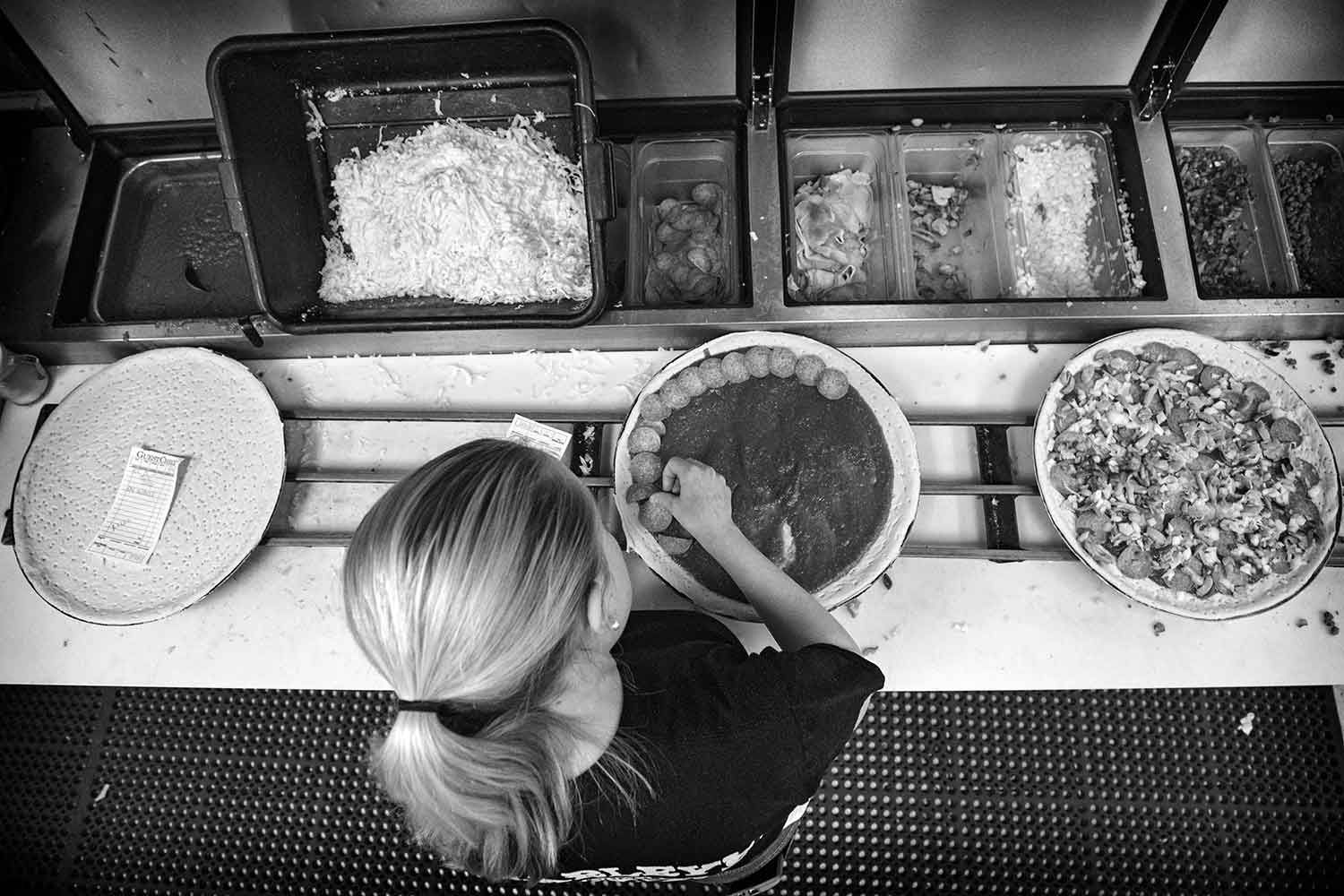 Ciarra Wallace places toppings on a pizza at Charleyʼs Pizza Parlor. photo by Austin Perryman - 2018