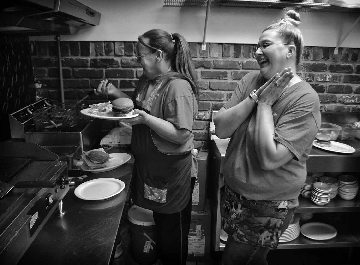 Diane Collins and Chris Goins share a laugh while preparing food at Katie’s Carry Out & Catering. photo by Alexandra Harper - 2014