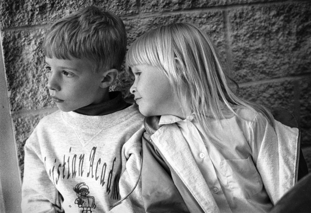 Waiting for their ride home after a long day at school, Will Ellison and Kelsey Leach look outside to see if their parents have arrived yet.  photo by Joshua Brown - 1997