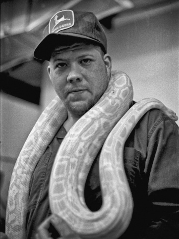 Kevin Dixon tries on a new boa at the World of Pets. photo by Matt Emigh - 1999