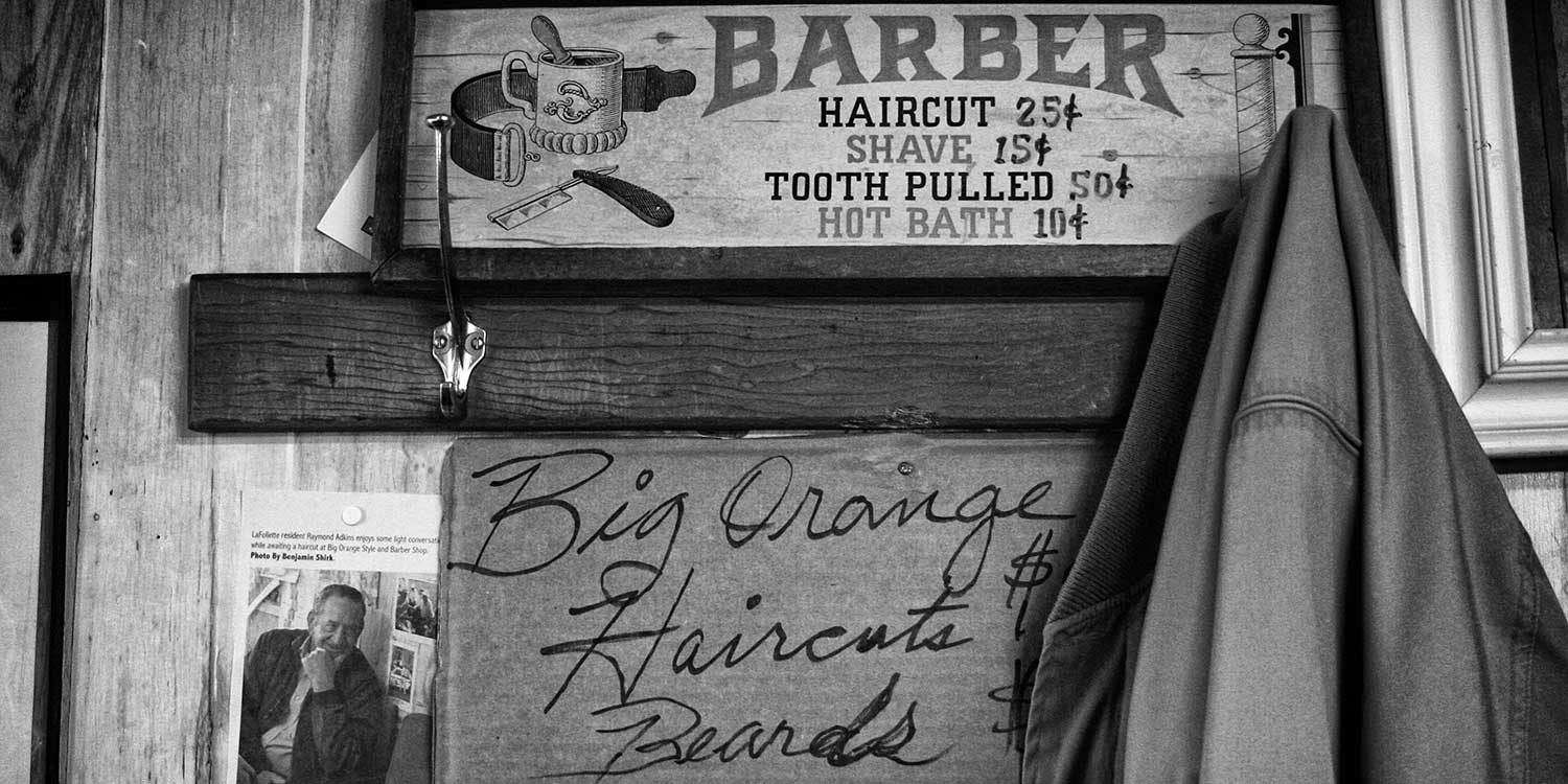 The Big Orange Barber Shop, located on Tennessee Ave., displays its current available services on a piece of cardboard directly below those of many years ago. photo by Ben Moser - 2009