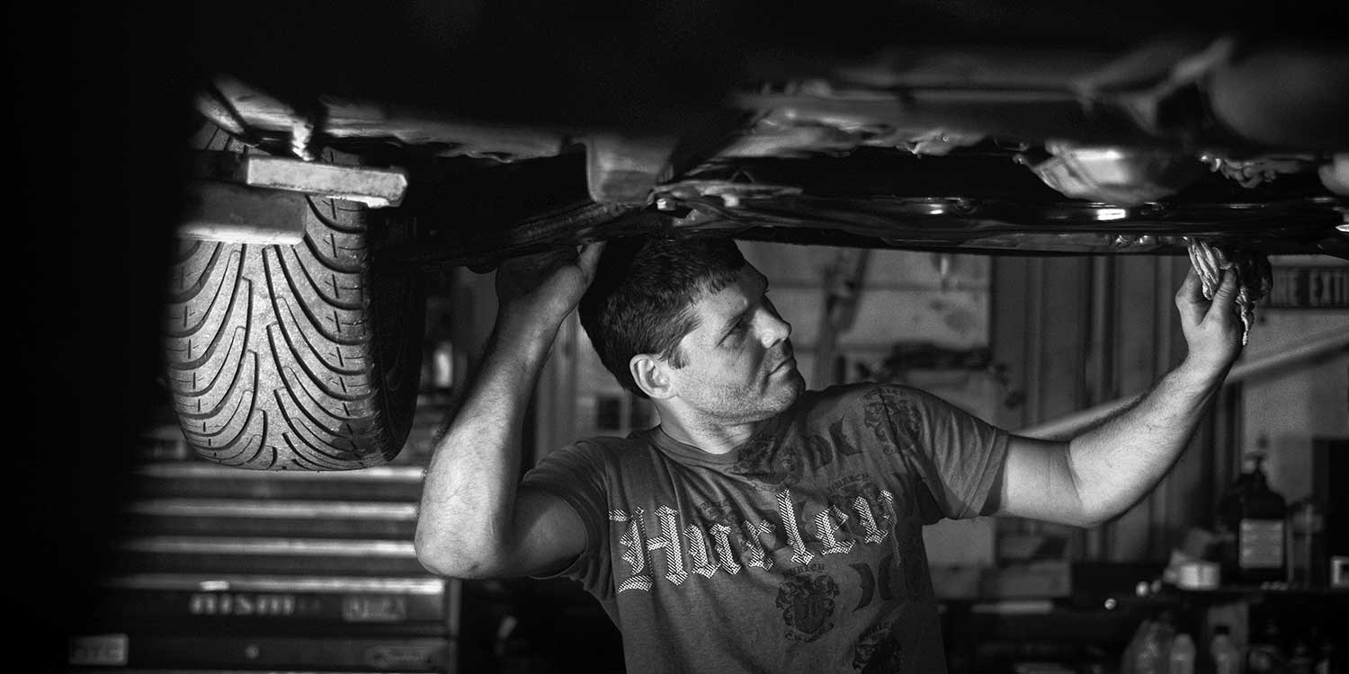 Brandon Johnson scrubs the underside of his car at his personal auto workshop. photo by Logan White - 2014